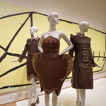 a grouping of three mannequins wearing Jeremy Scott designs in brown and gold