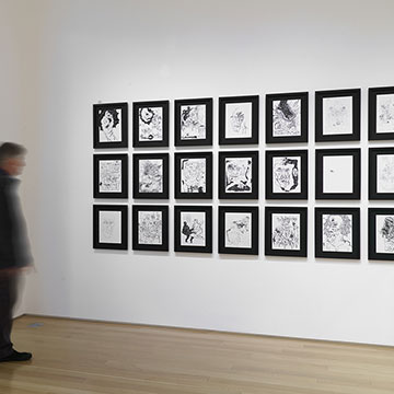 A museum visitor looks at drawings by Basil Kincaid
